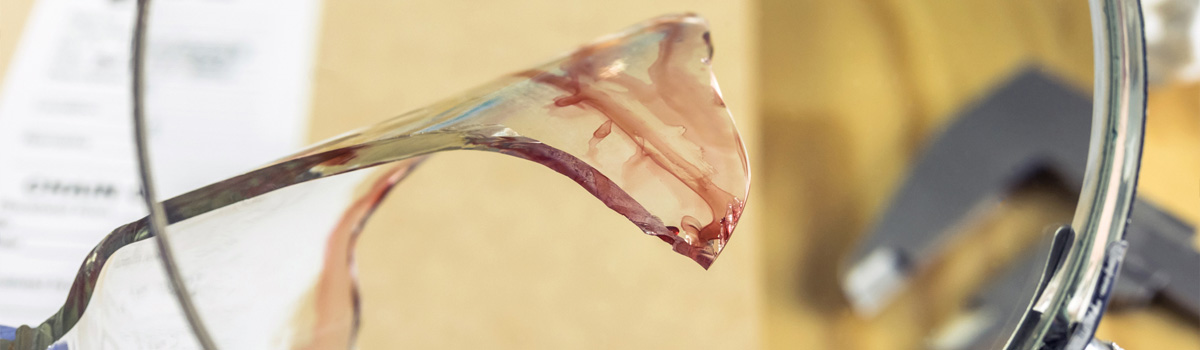 View of broken piece of glass with blood on it as seen through a magnifying glass